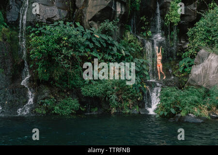 Frau im Bikini mit Wasserfall im Wald Stockfoto