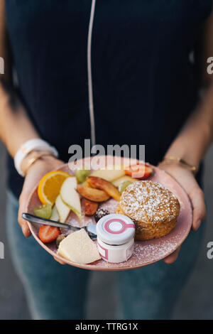 Mittelteil der Frau mit frischem Frühstück in der Platte im Cafe Stockfoto