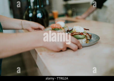 7/8 Hände von Frau Kommissionierung Platten mit Essen vom Tisch im Cafe Stockfoto