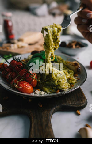 7/8 Hand von Frau Kommissionierung Spaghetti mit Gabel von der Platte im Restaurant Stockfoto