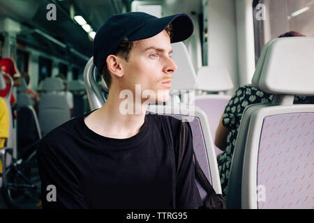 Nachdenklicher Mann mit Kappe entfernt bei Reisen im Zug suchen Stockfoto