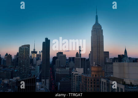 Das Empire State Gebäude mitten im Stadtbild gegen den klaren blauen Himmel bei Dämmerung Stockfoto