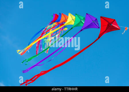 Eine Reihe von bunten Drachen auf einer einzelnen Zeile gegen ein strahlend blauer Himmel. Stockfoto