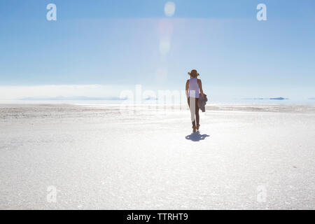 Ansicht der Rückseite Frau gehen auf Bonneville Salt Flats gegen den blauen Himmel während der sonnigen Tag Stockfoto