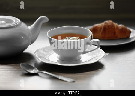 Tasse Kaffee mit Croissant auf Tisch Stockfoto