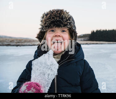 Portrait von verspielten Mädchen heraus haften Zunge halten Eis im Winter Stockfoto