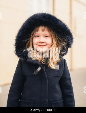 Portrait von lächelnden Mädchen mit Pelzmantel beim Stehen im Freien Stockfoto