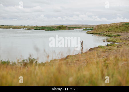 Hohe Betrachtungswinkel von Mann angeln im See gegen bewölkter Himmel Stockfoto