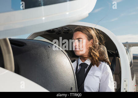 Nachdenklich weiblichen Piloten im Flugzeug sitzen gegen Himmel am Flughafen Stockfoto