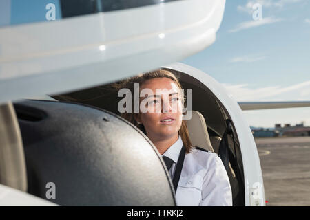 Nachdenklich weiblichen Piloten im Flugzeug sitzen gegen Himmel am Flughafen Stockfoto