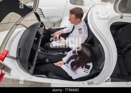 Hohe Betrachtungswinkel der männlichen pilot Leitprinzip weiblichen Auszubildenden beim Sitzen im Flugzeug am Flughafen Landebahn Stockfoto