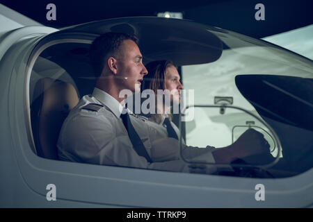 Seitenansicht des Piloten mit männlichen Auszubildenden fliegen im Flugsimulator Stockfoto