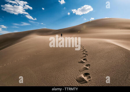 Mitte der Abstand der Wanderer zu Fuß auf Wüste gegen Himmel in der Great Sand Dunes National Park während der sonnigen Tag Stockfoto