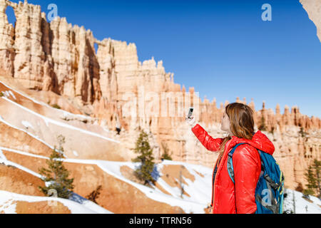 Wanderer Fotografieren durch Handy, während im Bryce Canyon National Park stehen Stockfoto