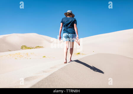 Ansicht der Rückseite Frau mit Flip-flop beim Gehen auf Sand bei Great Sand Dunes National Park während der sonnigen Tag Stockfoto