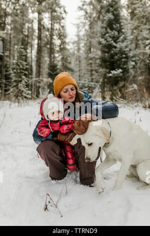 Mutter mit Tochter Streichelzoo Hund in Wald im Winter Stockfoto