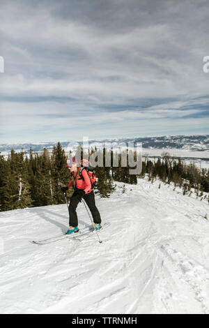 Frau mit Himmel wandern auf schneebedeckten Berg gegen bewölkter Himmel im Wald Stockfoto