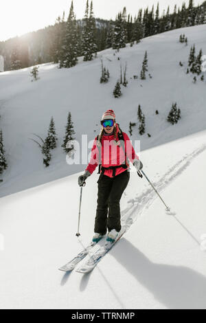 Frau Skifahren auf schneebedeckten Berg im Wald Stockfoto