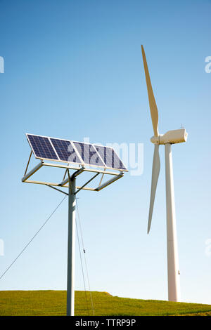 Windkraftanlagen und Solaranlagen auf gegen den klaren Himmel Stockfoto