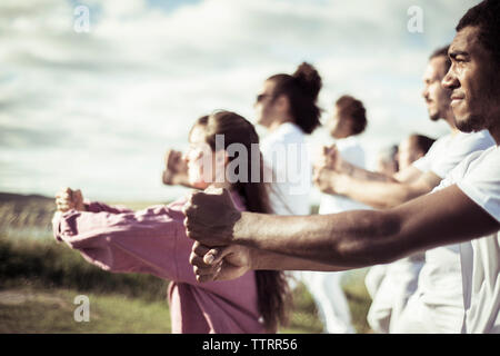 Seitenansicht der Freunde Ausübung auf Feld gegen Sky Stockfoto