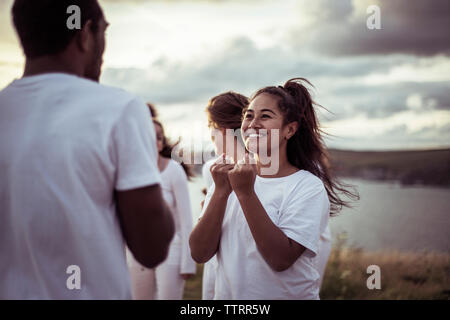 Freunde üben Entspannungsübung gegen bewölkter Himmel Stockfoto