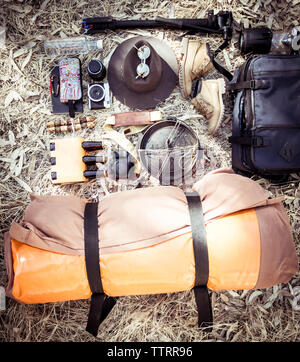 Hohe Betrachtungswinkel der Campingausrüstung mit persönlichen Accessoires auf dem Feld Stockfoto