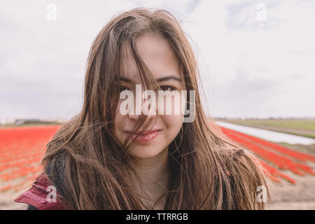 Junge Frau steht auf Feld Land mit Wind im Haar. Stockfoto