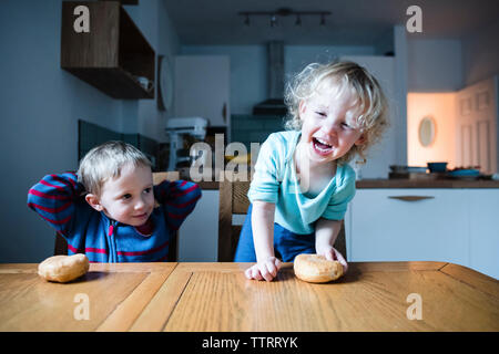 Geschwister mit Brötchen am Tisch Stockfoto