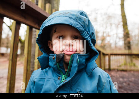 Porträt eines jungen herausragen Zunge stehend im park Stockfoto