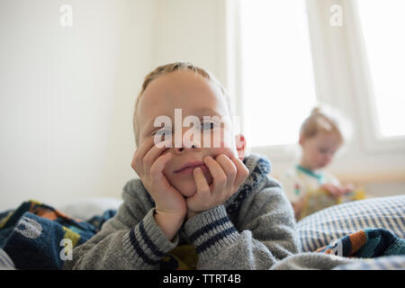 Nachdenkliche junge weg schauen beim liegen auf dem Bett mit Schwester im Hintergrund Stockfoto