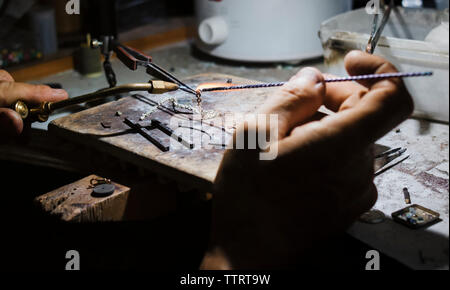 7/8 Hand des Menschen schweißen Kette in Werkstatt Stockfoto