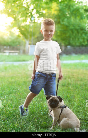 Süße Junge mit Mops Hund im Park