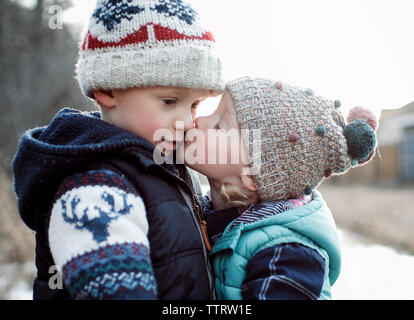 Liebevolle Schwester küssen Bruder im Winter Stockfoto