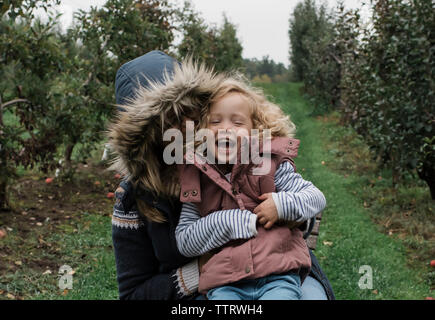 Glückliche Mutter mit Tochter sitzen auf der Wiese im Wald Stockfoto