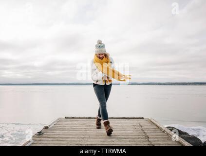 Frau zu Fuß auf den Pier am Strand mit See im Hintergrund Stockfoto