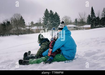 Vati Rodeln mit zwei Kinder im Schnee mit Spaß für die ganze Familie Stockfoto