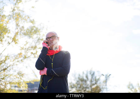 Ältere Menschen Sport tragen Kleidung beim Beantworten der smart phone gegen Himmel im Park Stockfoto