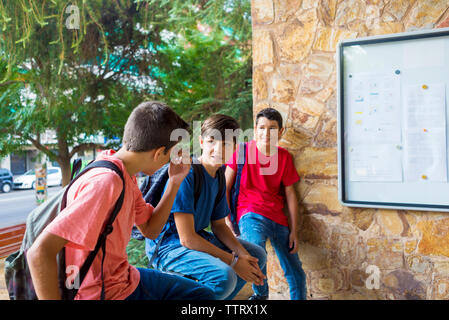 Freunde sprechen während der Sitzung gegen Bäume im Schulgebäude Stockfoto