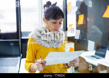 Trendy business Frau im Amt beim Lesen des Dokuments Stockfoto