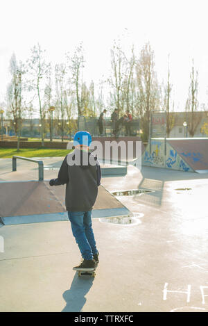 Ansicht der Rückseite des jungen Skater mit blauen Helm beim Skateboarden Stockfoto