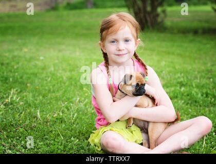 Portrait von nettes Mädchen mit Hund im Park sitzen Stockfoto