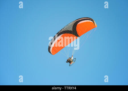 Low Angle View des jungen Mannes motor Paragliding gegen den klaren Himmel Stockfoto
