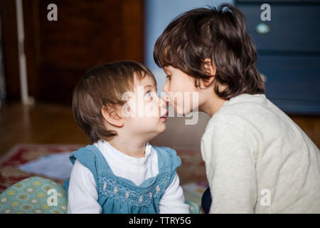 In der Nähe von Bruder küssen nette Schwester auf Nase, während zu Hause sitzen Stockfoto