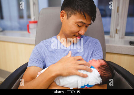 Ein stolzer neuer Vater blickt adoringly an seiner neugeborenen Tochter, schaukelnd Stockfoto