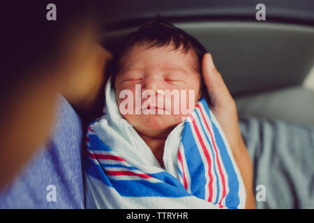 Eine Nahaufnahme eines neugeborenen Babys gewickelt in den Armen ihres Vaters in Halterung Stockfoto