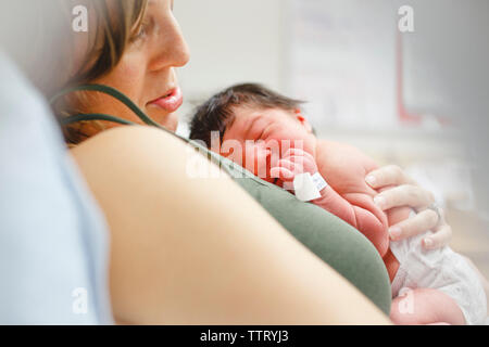 Seitliche Sicht auf eine zärtliche Mutter mit ihrem Neugeborenen in einem Krankenhausbett Stockfoto