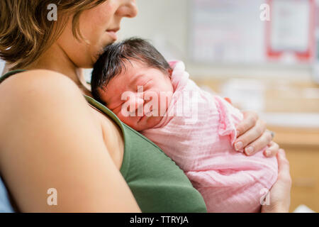 Seitliche Sicht auf eine neue Mutter mit ihrem neugeborenen Baby Mädchen im Krankenhaus Stockfoto