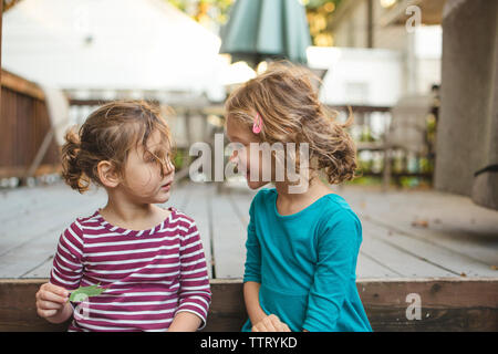 Zwei Mädchen sitzen gerne auf einem Deck im Gespräch Stockfoto