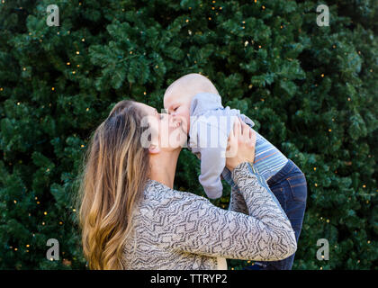 Eine Mutter hebt ihre baby boy für einen Kuss Stockfoto