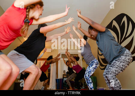 Ein lächelndes Gruppe von Yoga Schüler heben ihre Arme in Einklang Stockfoto